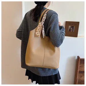 Detail of lychee pattern leather tote bag with silk scarf handle and fashion embossed tag