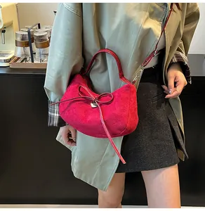 Détail du sac hobo bordeaux en daim avec grand nœud et breloque cœur sur bandoulière