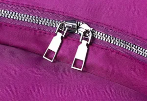 Detail van gladde zilveren metalen dubbele ritsen op een paarse nylon rugzak tas
