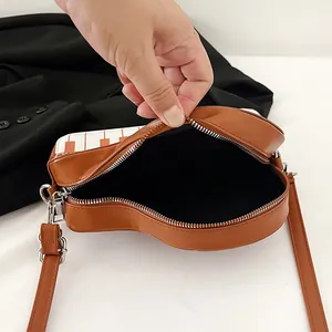 Bruine hartvormige crossbody tas met pianotoetsen ontwerp en open binnenvak detail