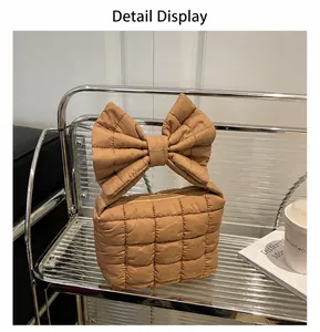 Detail view of brown quilted bag with large decorative bow on a glass shelf