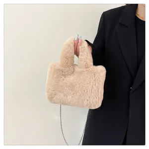 Detail of soft beige faux fur handbag with metallic chain strap worn by a model