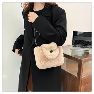 Detail of beige faux fur crossbody bag with silver chain strap on a black blazer