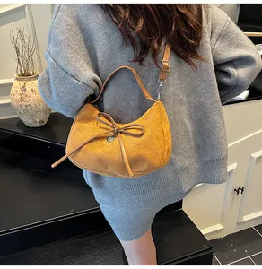 Détail du sac bandoulière demi-lune jaune avec nœud et breloque cœur porté par mannequin