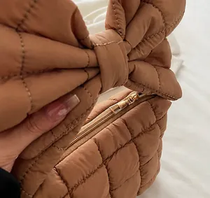 Detail of smooth gold zipper and quilted brown fabric on the bow shoulder bag