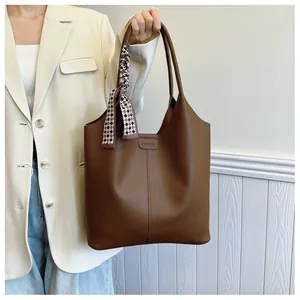 Close-up of brown tote bag showing lychee grain texture and decorative silk scarf detail