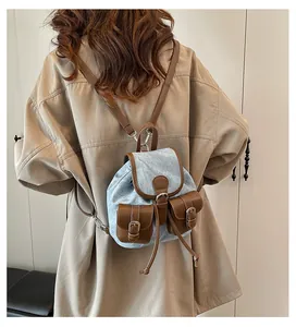 Détail d'un mini sac à dos vintage en jean et cuir porté sur un trench-coat élégant