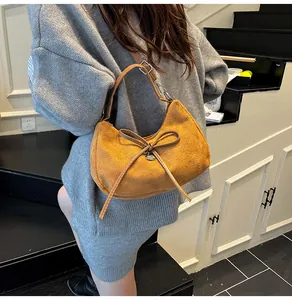 Détail du sac cabas jaune texture daim avec nœud en cuir marron et pendentif en cœur