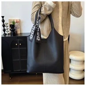 Detail of black pebbled leather tote bag with a stylish checkered silk scarf decoration