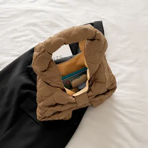 Quilted down tote bag in latte color showing interior capacity with a smartphone