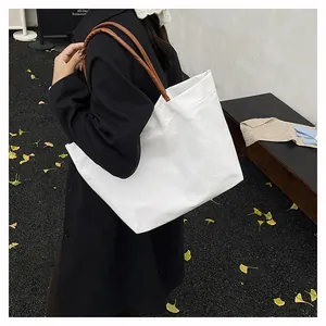 Vista detallada del bolso tote de lona blanco minimalista con asas marrones en el parque