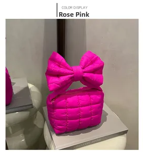 Detail view of rose pink quilted handbag with large bow decoration and checkered pattern
