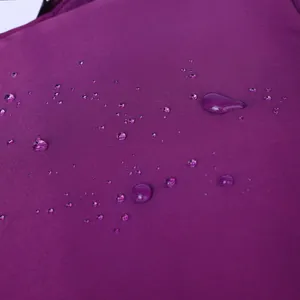 Detailopname van waterdichte paarse oxford stof met waterdruppels op een grote rugzak