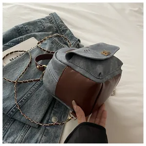 Detail of blue denim and brown leather mini backpack with metal chain straps