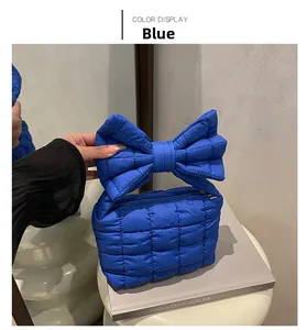 Detailed close-up of a blue quilted bow shoulder bag with padded fabric and zipper