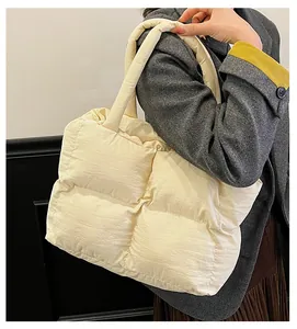 Detail shot of a large quilted down tote bag in cream white nylon for winter fashion