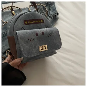 Detail of blue denim mini bag with cat ears, golden lock, and chain strap