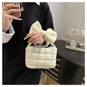 Detail van gewatteerde puffer tas met strikhandvat en gladde ritssluiting erop