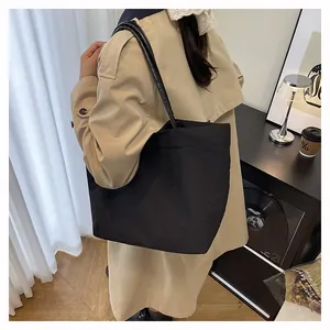 Vista detallada del bolso tote de lona negra con correas finas llevado por un modelo