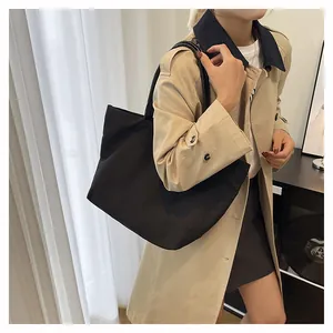 Detalle del bolso tote negro de lona minimalista con correas resistentes en modelo