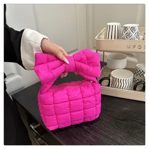 Detail van de grote strikhandgreep en de gewatteerde textuur op deze stijlvolle roze tas