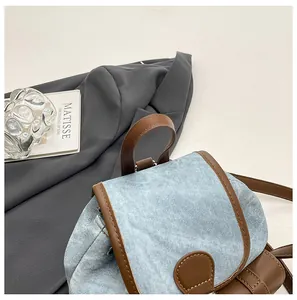 Détail d'un sac à dos en jean bleu clair avec garniture en cuir marron sur fond d'art