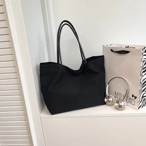 Bolso tote de lona negra minimalista con correas largas y gran capacidad de almacenaje