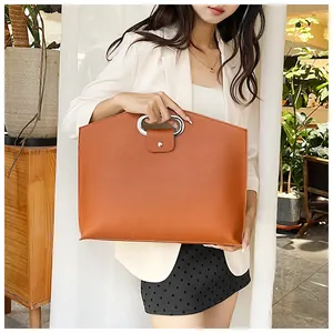 Detail of caramel orange leather tote bag with unique circular silver metal handle