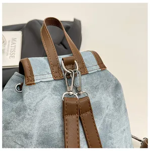 Détail du dos du sac à dos en jean avec bordure en cuir marron et boucles argentées