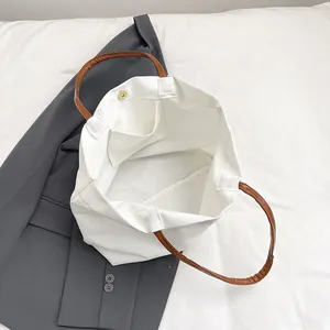 Bolso tote de lona blanca con asas de cuero marrón y cierre magnético de presión