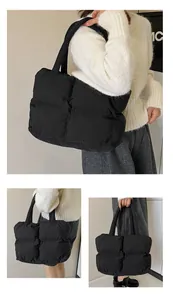 Detail of black quilted down tote bag with wide shoulder straps and puffy texture