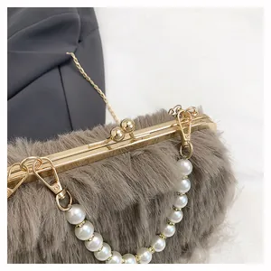 Dettaglio borsa in peluche grigio con manico di perle e chiusura in oro lucido