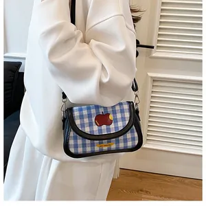 Detail shot of a blue and white checkered crossbody bag with an apple patch embroidery
