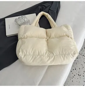Detail of soft quilted down tote bag in creamy white with thick padded handles
