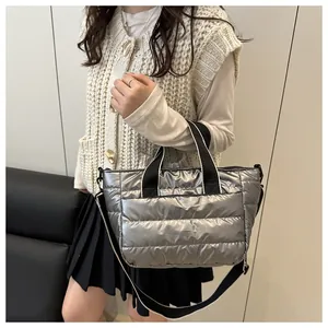 Detalle de bolso tote acolchado plateado metalizado con correas negras en modelo