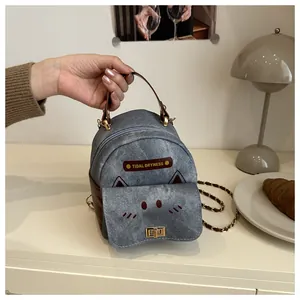 Close-up of mini denim backpack with cat embroidery, metal lock and chain strap