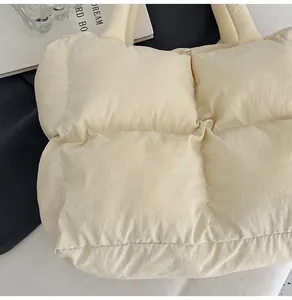 Close-up of beige quilted puffer tote bag with soft padded fabric and wide handles