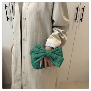 Detail van groene gewatteerde nylon clutch in strikvorm vastgehouden door een model