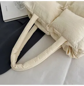 Close-up of cream quilted puffer tote bag showing soft texture and wide handle