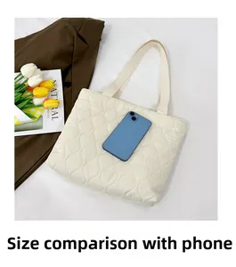 Detailed size comparison of white quilted tote bag next to a mobile phone