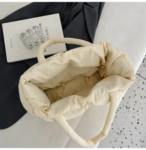 Overhead view of a quilted puffer tote bag in beige with a padded handle and large capacity