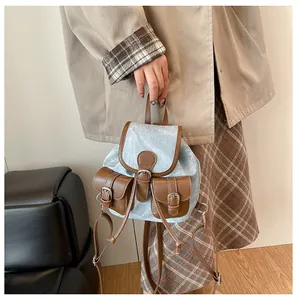 Détail du mini sac à dos en denim avec finitions en cuir marron et boucles en métal