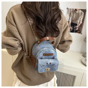 Detail of blue denim backpack with cat ears, metal chain straps and leather logo