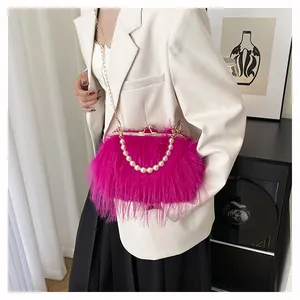 Dettaglio borsa in piuma magenta con catena di grandi perle e chiusura in metallo dorato