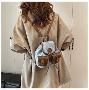 Détail d'un sac à dos rétro en denim et cuir marron avec fermeture à cordon et sangles