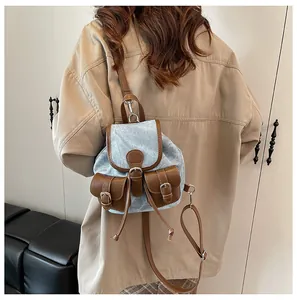 Détail d'un mini sac à dos en jean vintage avec garnitures en cuir brun et boucles
