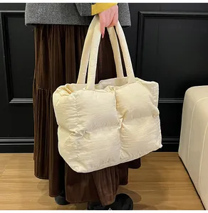 Model wearing a large cream quilted puffer tote bag in a minimalist interior setting