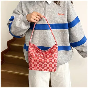 Detail view of the red Chinese Xi character jacquard knit tote bag held by a model