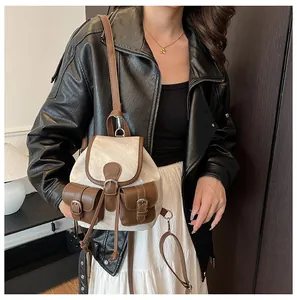 Sac à dos rétro beige avec garniture en cuir brun et boucles en métal porté par un modèle