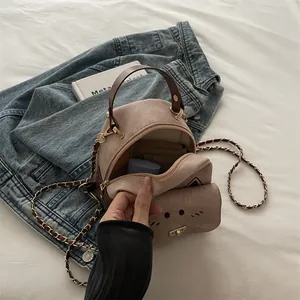 Cat-shaped round crossbody bag in mauve suede with metal chain and top handle